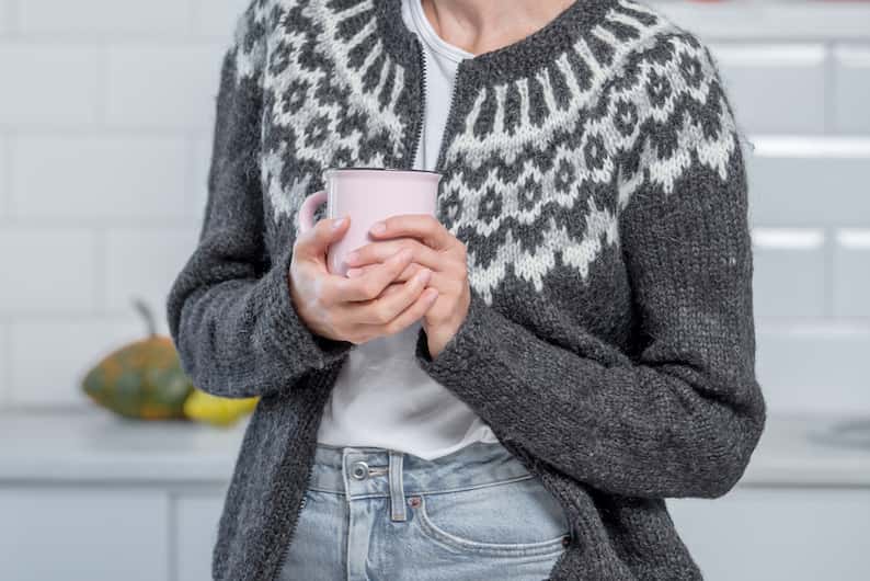 woman wearing a sweater holding a coffee
