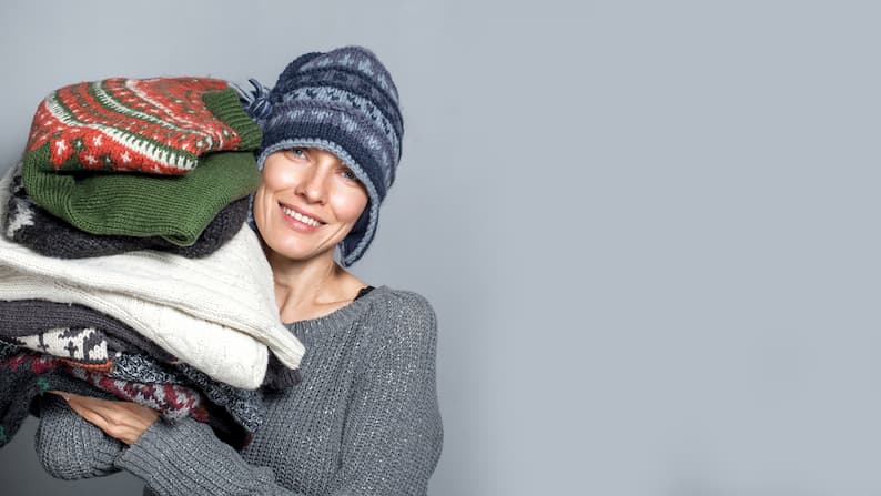 woman carrying sweaters from some of the best Norwegian brands