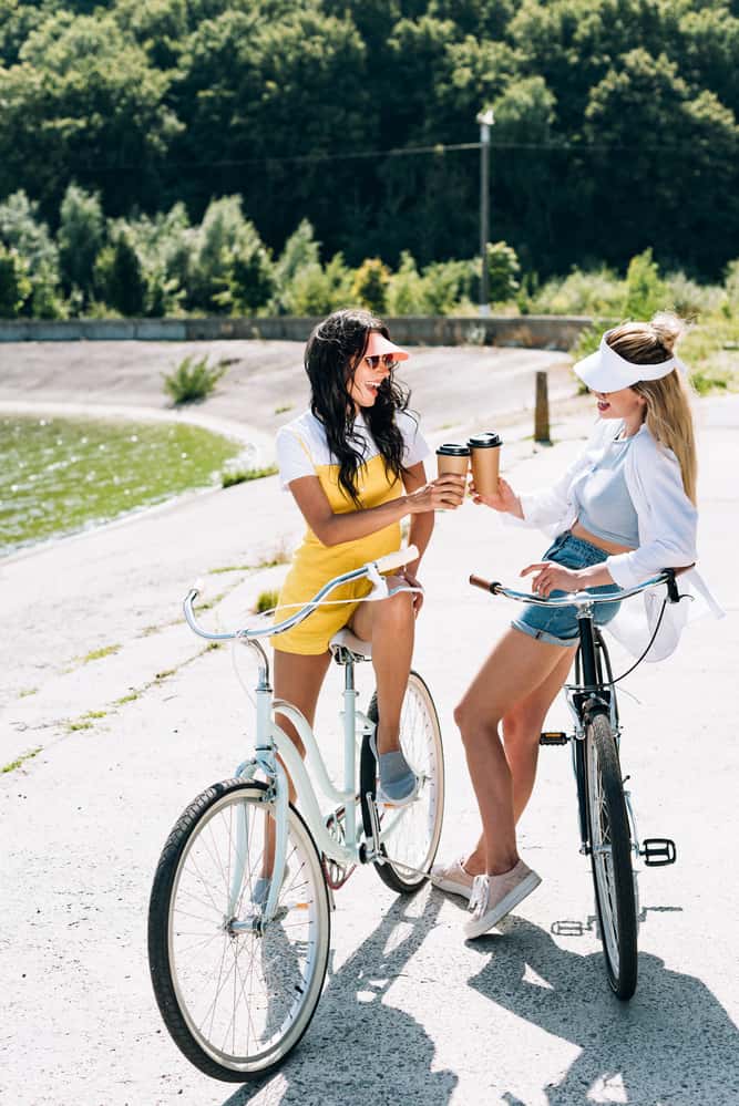 two friends on bikes drinking coffee together