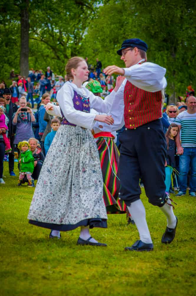 man in Swedish traditional clothing for males dancing with a woman