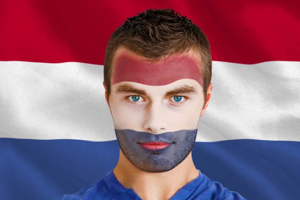 a man painted red and blue behind the Netherlands flag to know the difference between Danish vs Dutch