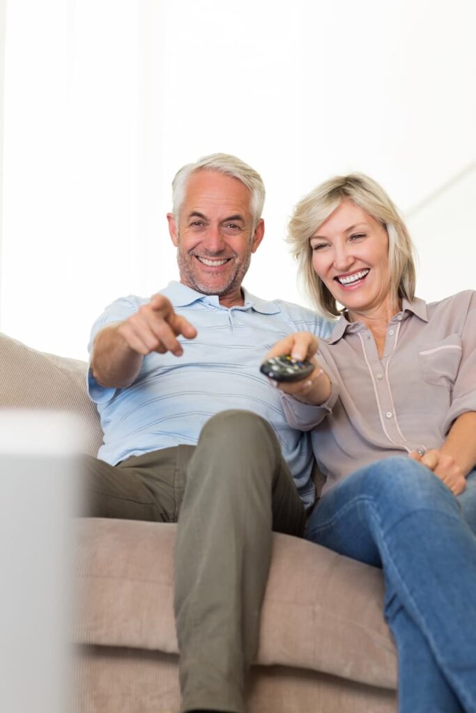 a couple sitting on a couch holding a remote control while watching Scandinavian tv shows