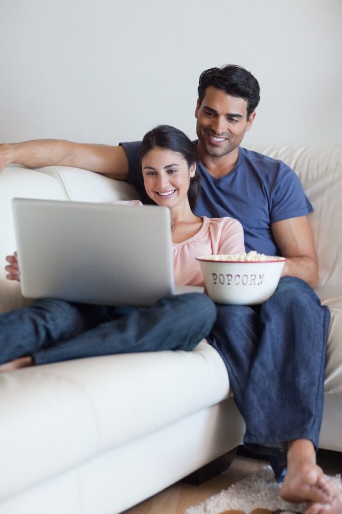 a couple with a bowl of popcorn watching Scandinavian tv shows on their laptop